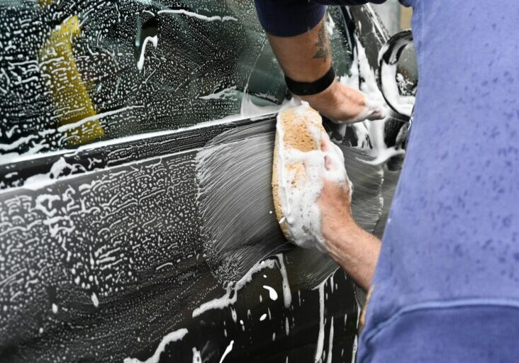 a man washing a car with a sponge